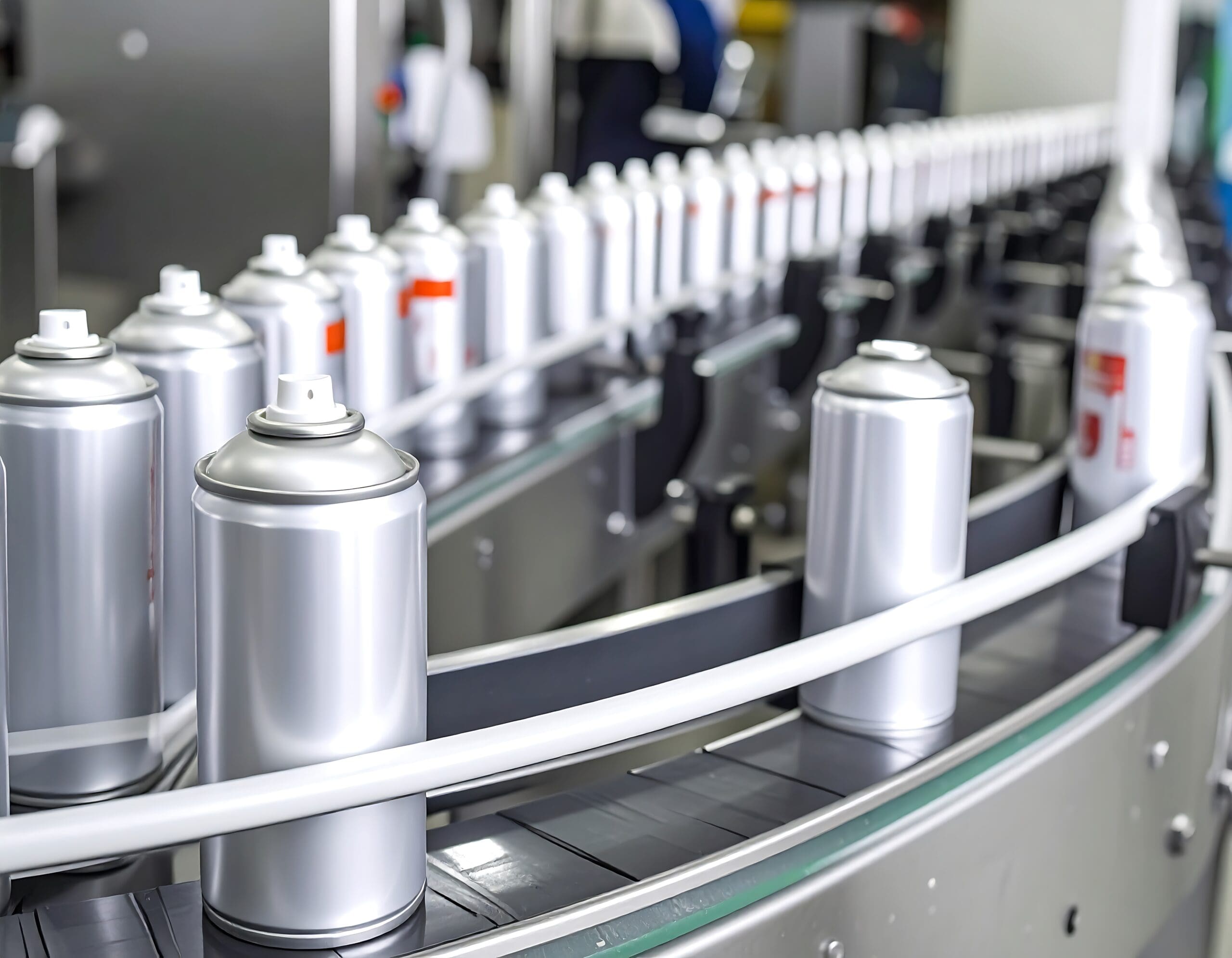 Silver spray cans on a conveyor belt in a factory